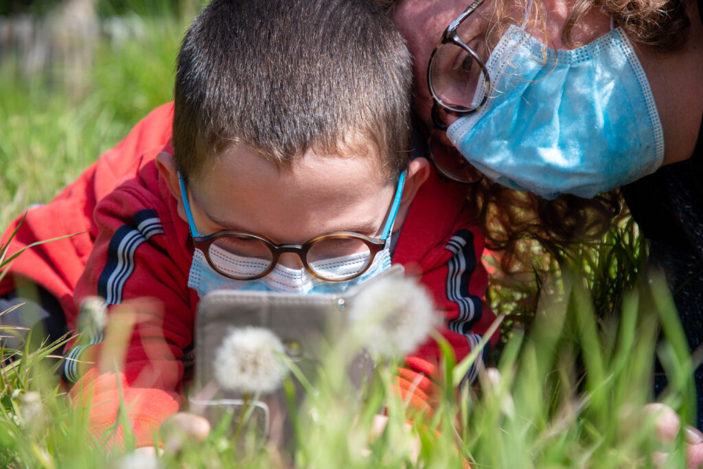 Un enfant prenant une fleur en photo avec un smartphone